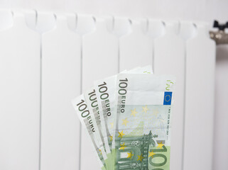 A close-up of a hundred euro banknote. In the background, the battery is white. The concept of high payments for heat in winter in Europe. The crisis of energy resources, the increase in utility bills