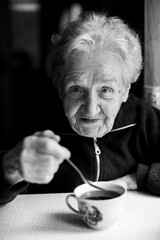 Portrait of a grandmother with a cup of tea. Black and white photo.