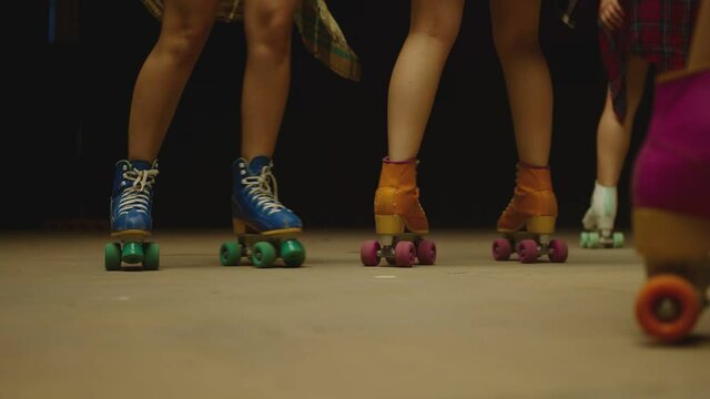 Female legs in roller blades, skating fast at the roller park on floor . Close-up legs of young women is professionally skating . Different kind of and colorful vintage roller blades . Slow Motion