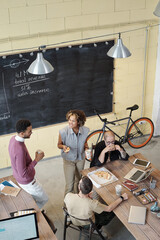 Young contemporary office managers interacting at lunchc break while having pizza by workplace