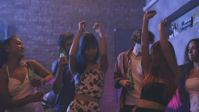 Diverse group of young people dancing at the night club, enjoying nightlife and drink