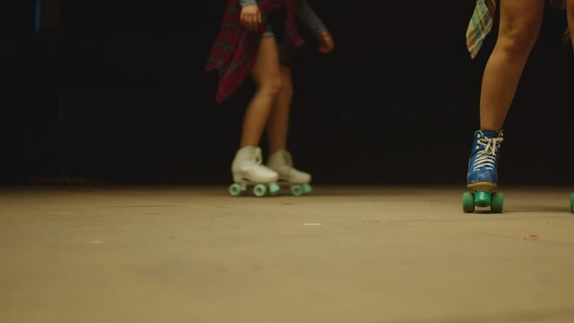 Female legs in roller blades, skating fast at the roller park on floor . Close-up legs of young women is professionally skating . Different kind of and colorful vintage roller blades . Slow Motion