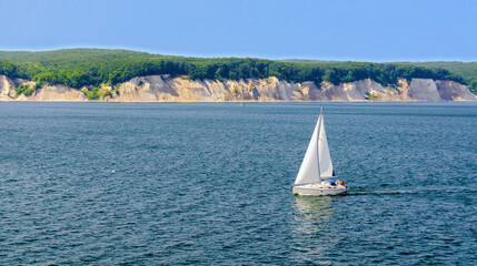 Sailing boat on blue water at the Baltic sea before the chalk cliffs of  the isle of Ruegen, Germany