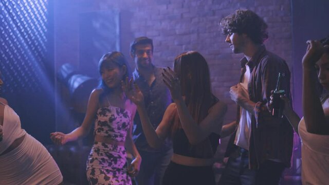 Diverse group of young people dancing at the night club, enjoying nightlife and drink