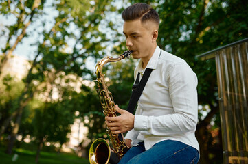 Young saxophonist plays the saxophone in park