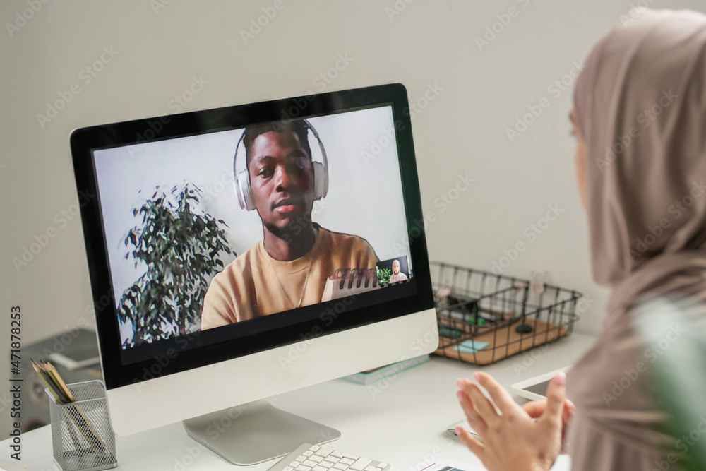 Poster young african student on computer screen looking at his teacher in hijab explaining him some points 