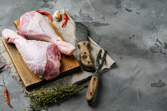 Fresh uncooked turkey legs, on wooden cutting board, on gray stone table background, with copy space for text