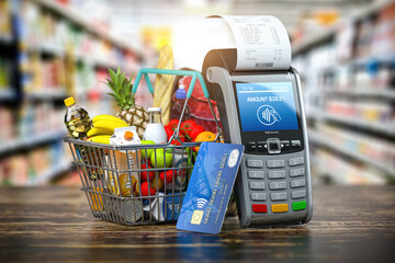 Buying food and drink online. Shopping basket with food and POS terminal and cedit card in grocery store.