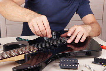 Guitar technician checking radius of strings on modern electric guitar.