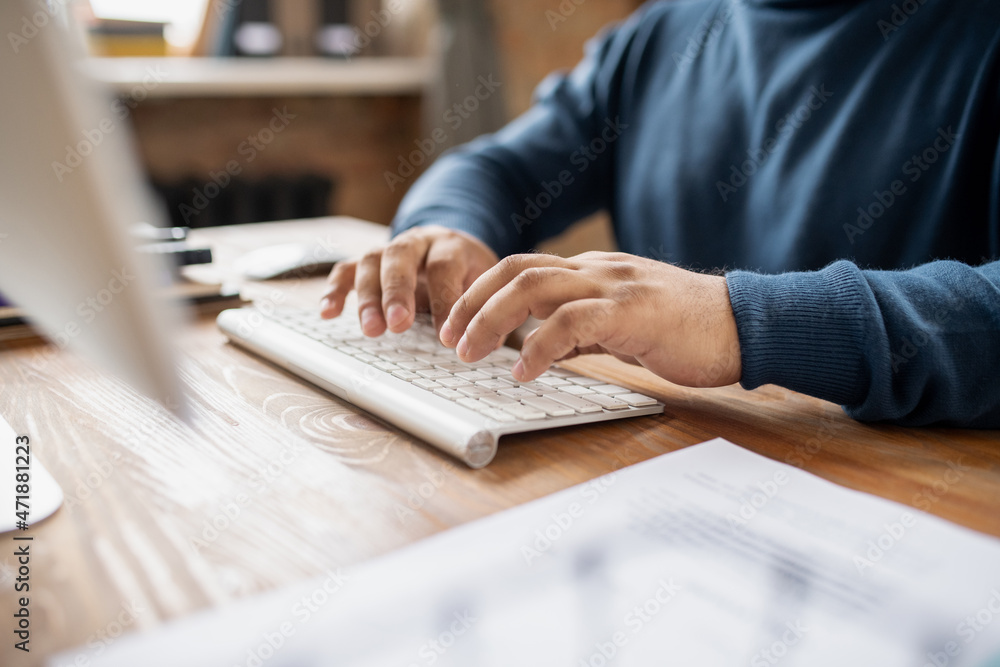 Poster Contemporary businessman or teacher pressing buttons of keypad while sitting by table in front of computer and working