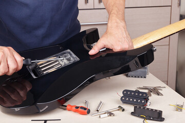 Guitar repairer adjusts springs of tremolo bridge on modern electric guitar.