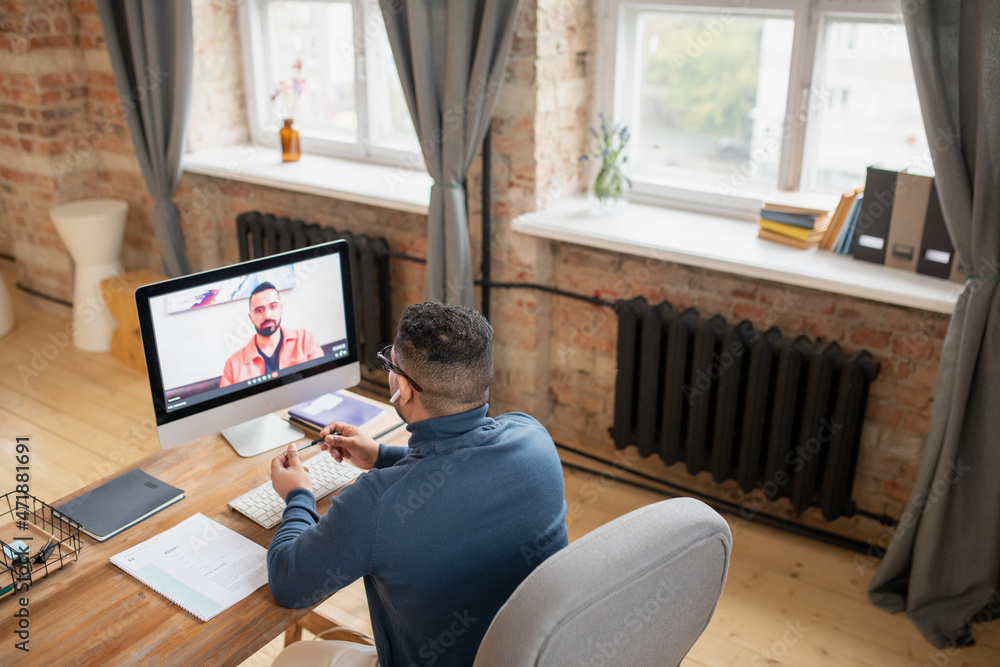 Aufkleber mature man sitting in front of computer monitor and communicating to his teacher on screen during on