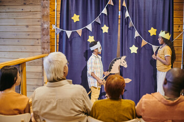 Two cute interracial siblings in handmade stage costumes performing in front of audience during home theatre play