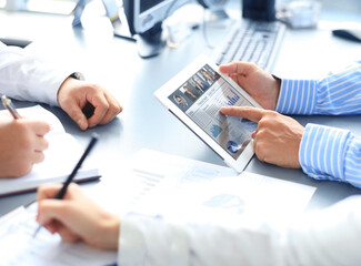 Close up of person video conferencing with colleagues on digital tablet, analyzing financial statistics displayed on the digital tablet screen.