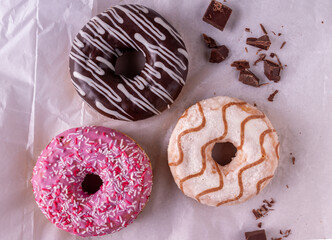 donuts drizzled with sugar glaze lie on white culinary paper