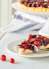 Close up of a piece of cranberry tart with the full pie in behind.