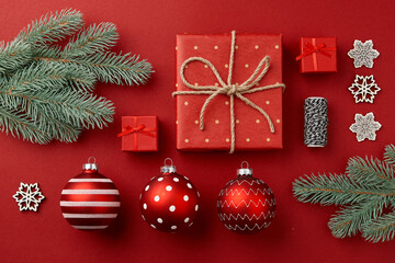 Christmas composition. Gifts christmas tree branches and ornaments on red background