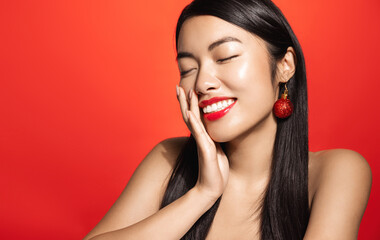 Winter holidays, sale and fashion concept. Beautiful asian female model with red lips, clear facial skin, laughing and smiling, touching healthy glowing face with satisfaction