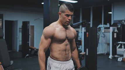Obraz na płótnie Canvas Muscular arab man training with dumbbells in the gym.