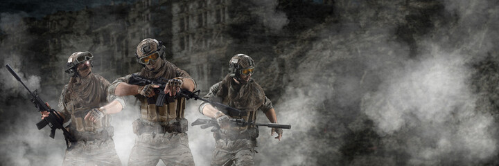 Three mercenary soldiers during a special operation in the smoke against the background of a ruins - photo with copy space. Format photo 3x1.