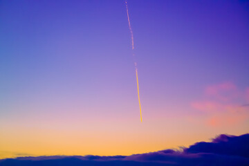 Contrail in amazing sundown sky with fluffy clouds