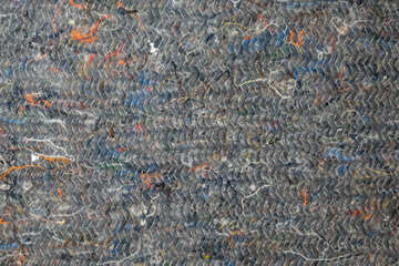 Close-up of a gray rag for cleaning the floor. The fabric is made of textile waste, stitched with threads. There are multi-colored fibers. Background. Texture.