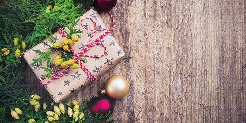 Christmas background with fir branches, toys, gift box and bells on wooden old background table. Selective focus. Top view with copy space