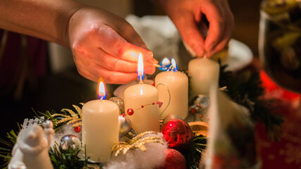 Obraz na płótnie Canvas detail of a woman lighting an advent candle
