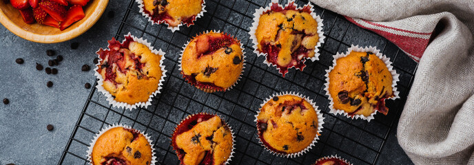 Strawberry chocolate cupcakes muffins on old wooden stand on concrete gray background. Top view