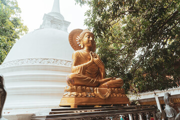 Złoty posąg buddy na tle świątynni buddyjskiej.