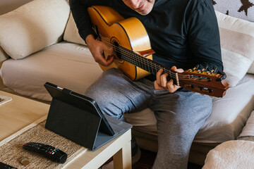 Man taking guitar lessons at home.