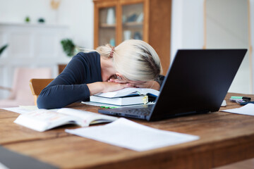 Female student preparing for exams and has her head resting on books.