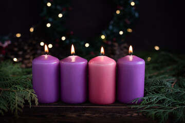 A row of four burning purple advent candles Christmas concept.