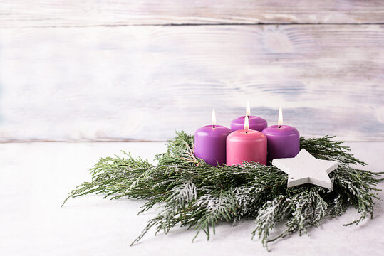 Wreath with four purple advent candles on a white background.