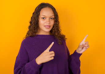 teenager girl wearing purple knitted sweater against yellow background with positive expression,...