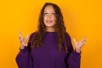 teenager girl wearing purple knitted sweater against yellow background crying and screaming. Human emotions, facial expression concept. Screaming, hate, rage.
