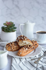 sweet French breakfast: coffee and eclairs on a light grey table
