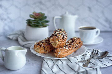 Obraz na płótnie Canvas sweet French breakfast: coffee and eclairs on a light grey table 