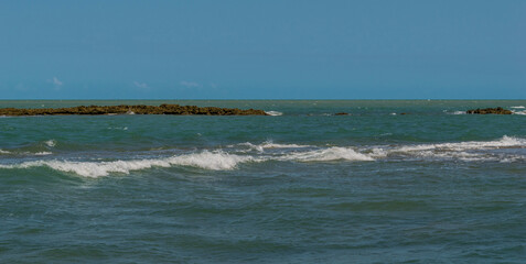 Linda vista de praia com muitas pedras e um céu azul
