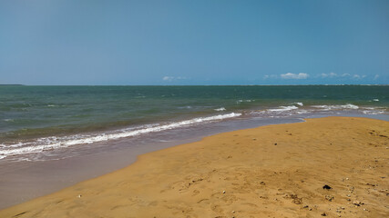 Linda vista de praia com areias escuras e um céu azul