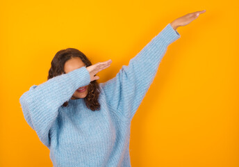 Photo of funky Teenager girl wearing blue sweater over yellow background show disco move dab