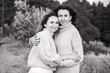 Black and white photo with girls hugging. Two brunettes in warm sweaters. Close relationships...