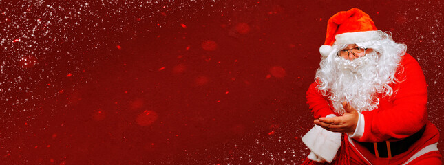 Santa Claus sits on a chair in an interrogative position with an outstretched hand on a festive red Christmas background with snowflakes. Panoramic banner with copy space