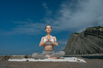 Naklejka na ściany i meble Yoga practice and meditation in nature. Woman practicing near Black sea.