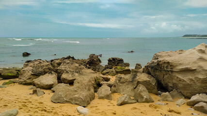 Linda vista de praia com muitas pedras e um céu azul