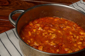Chicken goulash in metal cooking pot on wooden table