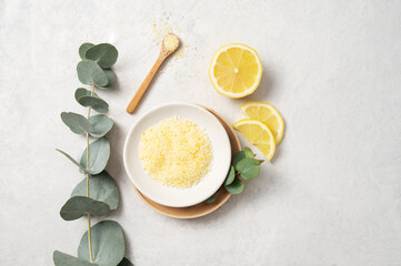 Fototapeta na wymiar Organic yellow sea salt with lemon and eucalyptus branch on a white textured background. The concept of spa and wellness. Top view and copy .space