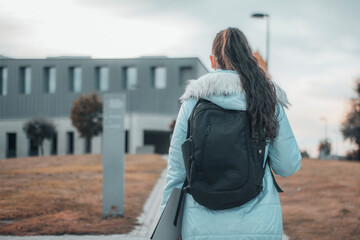 Obraz premium Muchacha joven con chaqueta paseando por el campus de la universidad con mochila para entrar al aula 