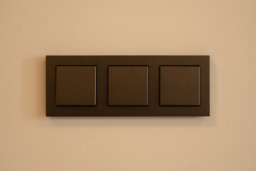 Three position light switch in brown on a white background.