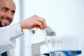 smiling scientist holds a test tube with a sample of the vaccine .